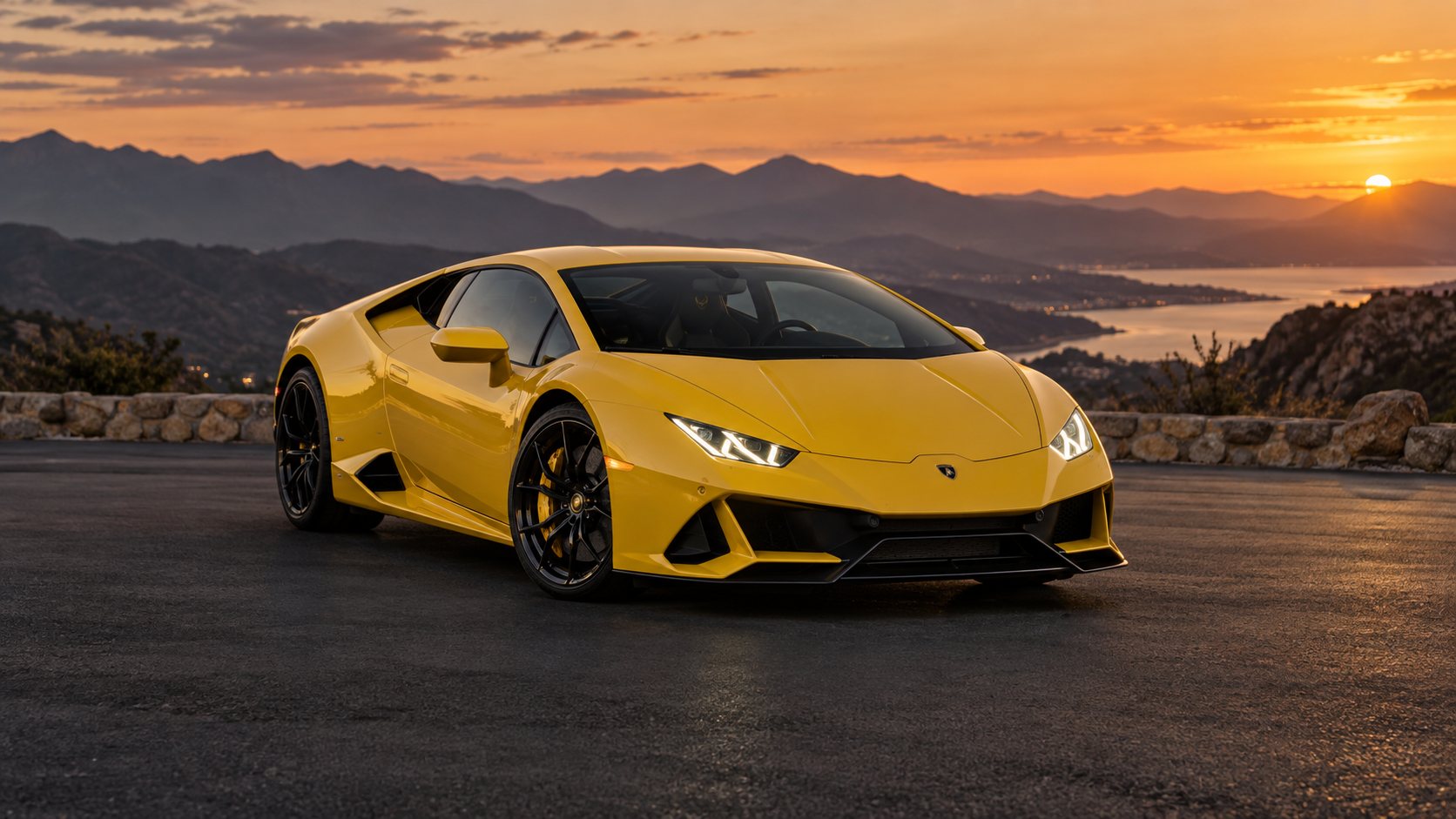 Yellow Lamborghini Huracan overlooking the mountains at sunset